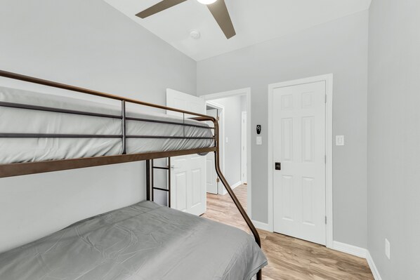 A room with a bunk bed, white walls, a wooden floor, and a ceiling fan. - 🍊 Home Away from Home (Houston)