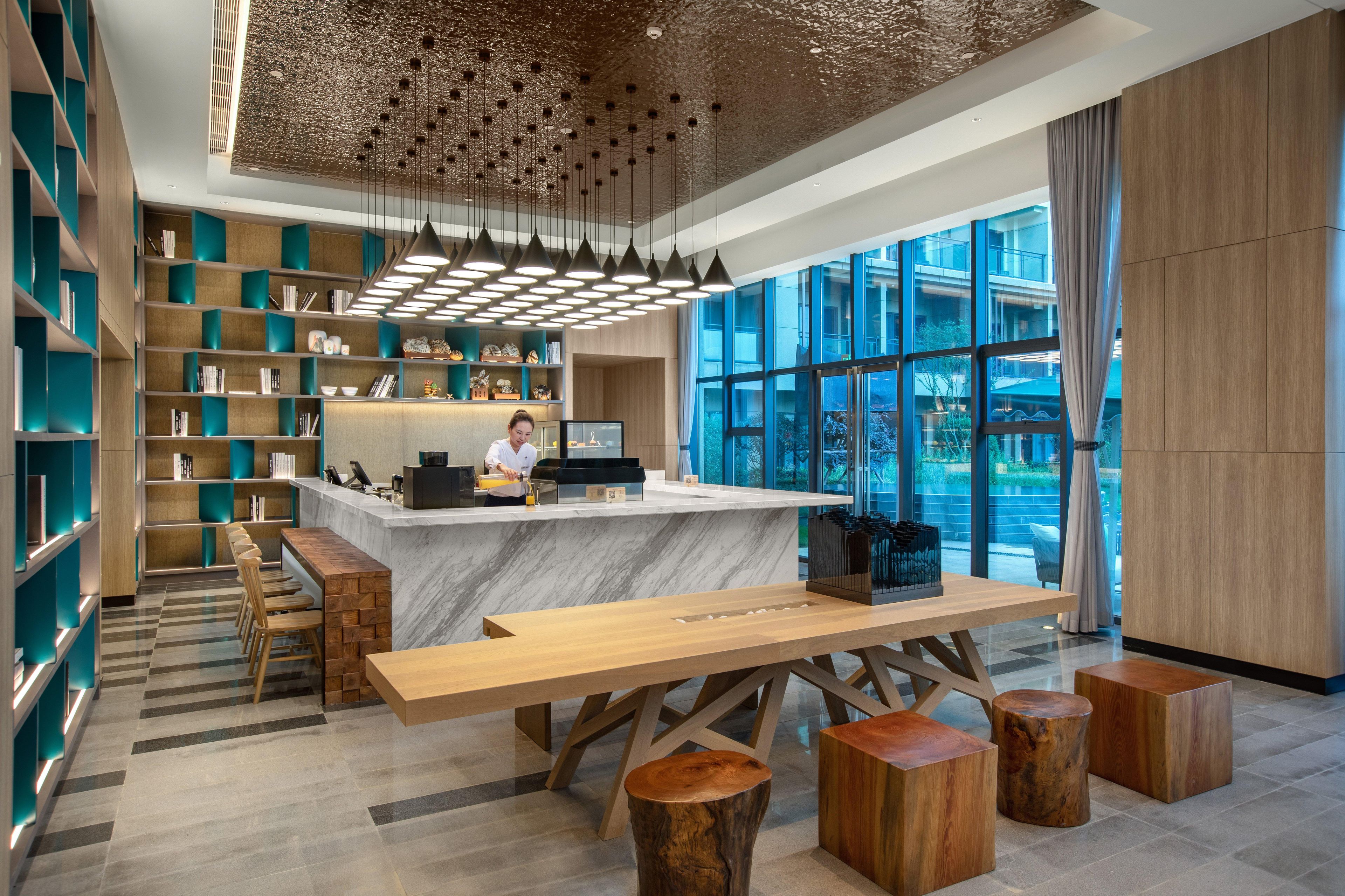 A modern reception area with a marble counter, wooden furniture, and a view through large windows.