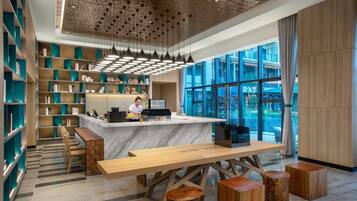 A modern reception area with a marble counter, wooden furniture, and a view through large windows.