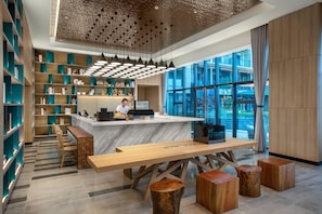 A modern reception area with a marble counter, wooden furniture, and a view through large windows.