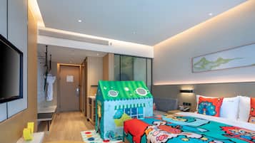 A modern hotel room with a bed, a playhouse, a TV, and a large window.