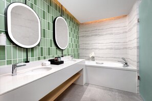 Une salle de bain moderne avec deux lavabos, une baignoire et deux grands miroirs.