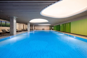 A swimming pool with a blue floor, lounge chairs, and a reception area.