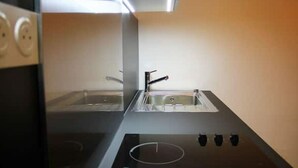 Eine moderne Küche mit schwarzem Arbeitsplatz, Edelstahlspüle und eingebautem Backofen.