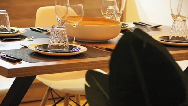 A dining table set with plates, glasses, and cutlery, with a bowl and a bottle visible. - Upscale apartment downtown Colmar (Colmar)