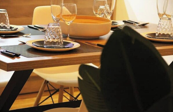 A dining table set with plates, glasses, and cutlery, with a bowl and a bottle visible.