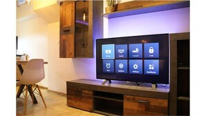 Ein Flachbildfernseher an einer Holzeinrichtung mit eingebautem Ablagebereich darunter.