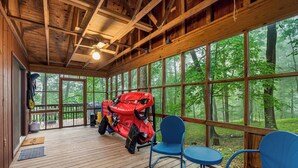 A wooden deck with a ceiling fan, large windows, and outdoor seating.