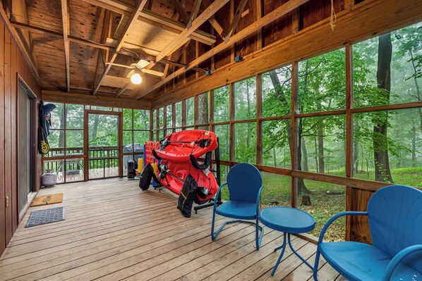 A wooden deck with a ceiling fan, large windows, and outdoor seating. - River Cabin w/ Hot Tub, Screened Porch & Fire Pit (Great Cacapon)
