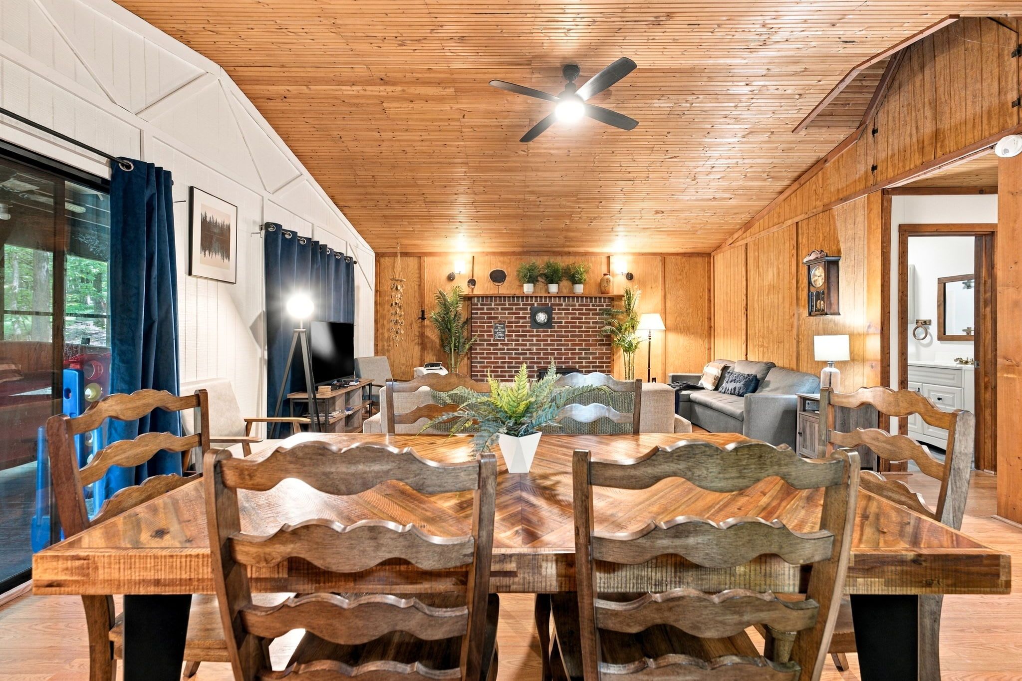 Un coin repas avec une table et des chaises en bois, un téléviseur et un ventilateur de plafond.