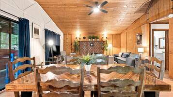 Un coin repas avec une table et des chaises en bois, un téléviseur et un ventilateur de plafond.