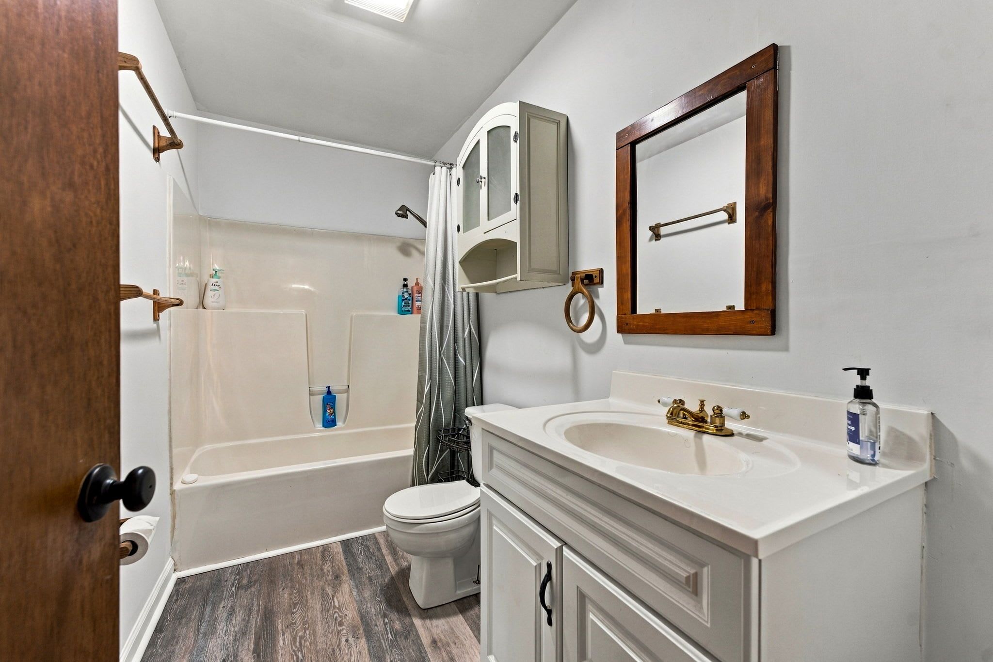 A bathroom with a bathtub, toilet, sink, and mirror.