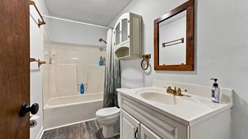 A bathroom with a bathtub, toilet, sink, and mirror.