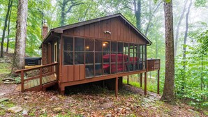 A wooden cabin with a glass front, surrounded by trees.