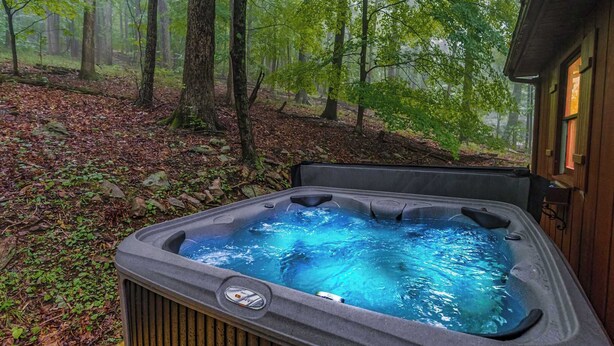 A hot tub in a forested area with a wooden deck.