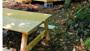A tent with a table and chairs in a wooded area. - 100 Acre Whispering Woods (Livermore Falls)