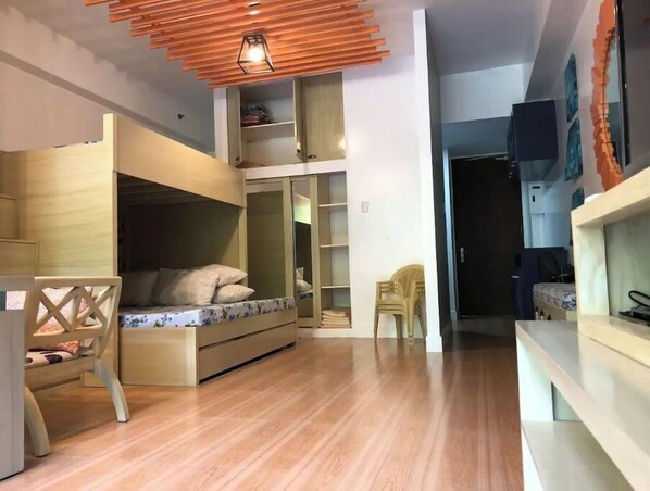 A compact room with a bunk bed, built-in shelving, and a small desk.