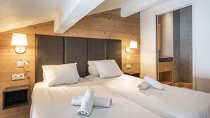 Una camera d'albergo con una testiera in legno, due letti, lampade sui comodini, una mensola a incasso e una grande finestra.