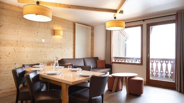 Un'area pranzo con un tavolo di legno apparecchiato per quattro persone, un divano e un piccolo tavolino rotondo.