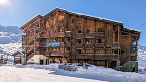 A wooden chalet with multiple balconies and a sign indicating it is a ski resort. - Wifi, ski-in/ski-out & foot of the slopes, fitness, swimming pool, sauna, hammam, balcony (Val Thorens)