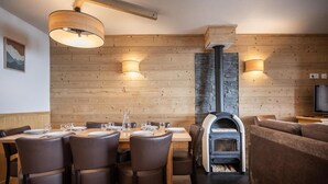 A dining area with a wooden wall, a stone fireplace, and a television. - Wifi, ski-in/ski-out & foot of the slopes, fitness, swimming pool, sauna, hammam, balcony (Val Thorens)