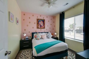 A bedroom with a bed, a ceiling fan, a window with blinds, and a door. - East Nashville pop-art apartment, sleeps 12, 4BR near downtown (Nashville)