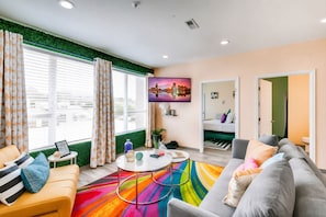 A modern living room with a sofa, armchair, and a colorful rug.