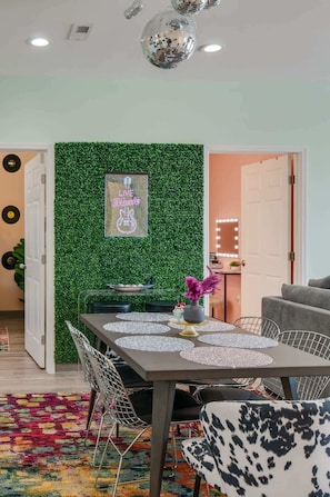 Un comedor con pared verde, una mesa con un centro de mesa decorativo y un sofá.