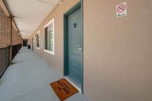A hallway with doors, a no-smoking sign, and a doormat that says "It's always happy hour here." - East Nashville pop-art apartment, sleeps 12, 4BR near downtown (Nashville)