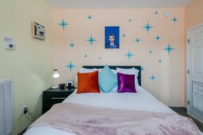 A bedroom with a bed, a nightstand, a lamp, and a wall with star decorations.