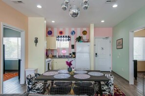 A modern kitchen with a central island, a dining area with a table and chairs, and a living space with a sofa and a TV. - East Nashville pop-art apartment, sleeps 12, 4BR near downtown (Nashville)