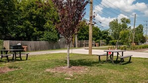 A picnic area with two tables and benches, surrounded by grass and trees.