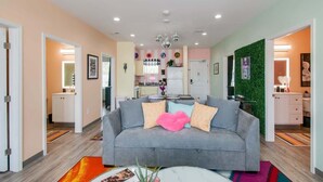 A modern living room with a grey sofa, a coffee table, and a kitchen in the background.