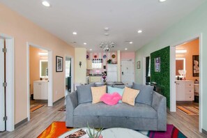 A modern living room with a grey sofa, a coffee table, and a kitchen in the background.