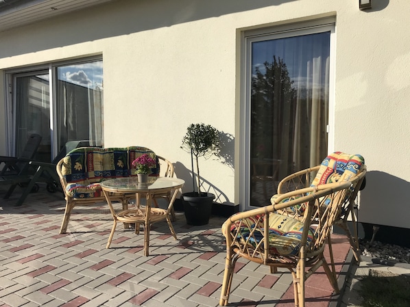 Relax in a serene outdoor space with a round table, wicker chairs, and a potted plant.