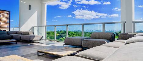 A modern outdoor seating area with a city view, large windows, and a pergola structure.