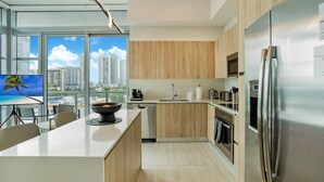 Een moderne keuken met een groot eiland, roestvrijstalen apparatuur en uitzicht op de stad.