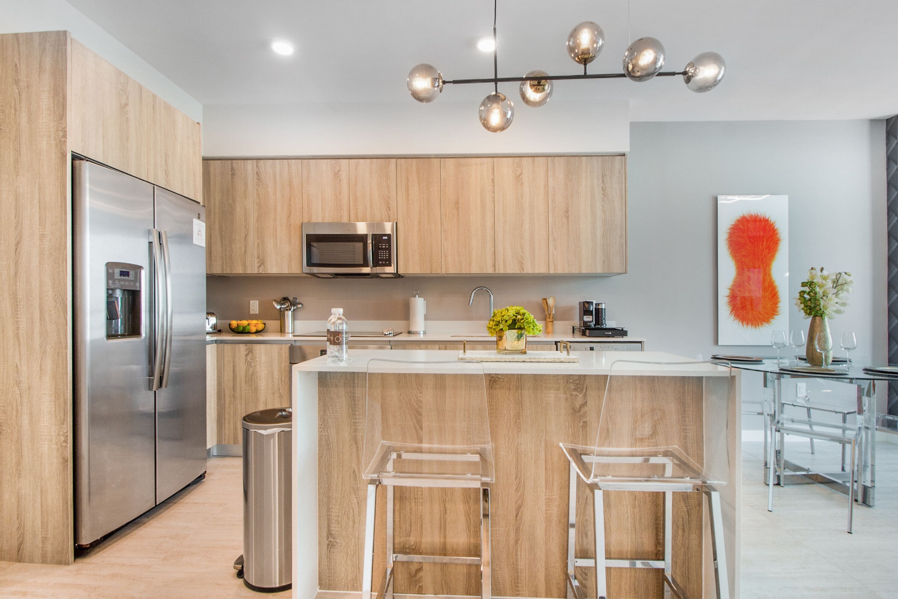A modern kitchen with wooden cabinets, stainless steel appliances, and a central island with bar stools.