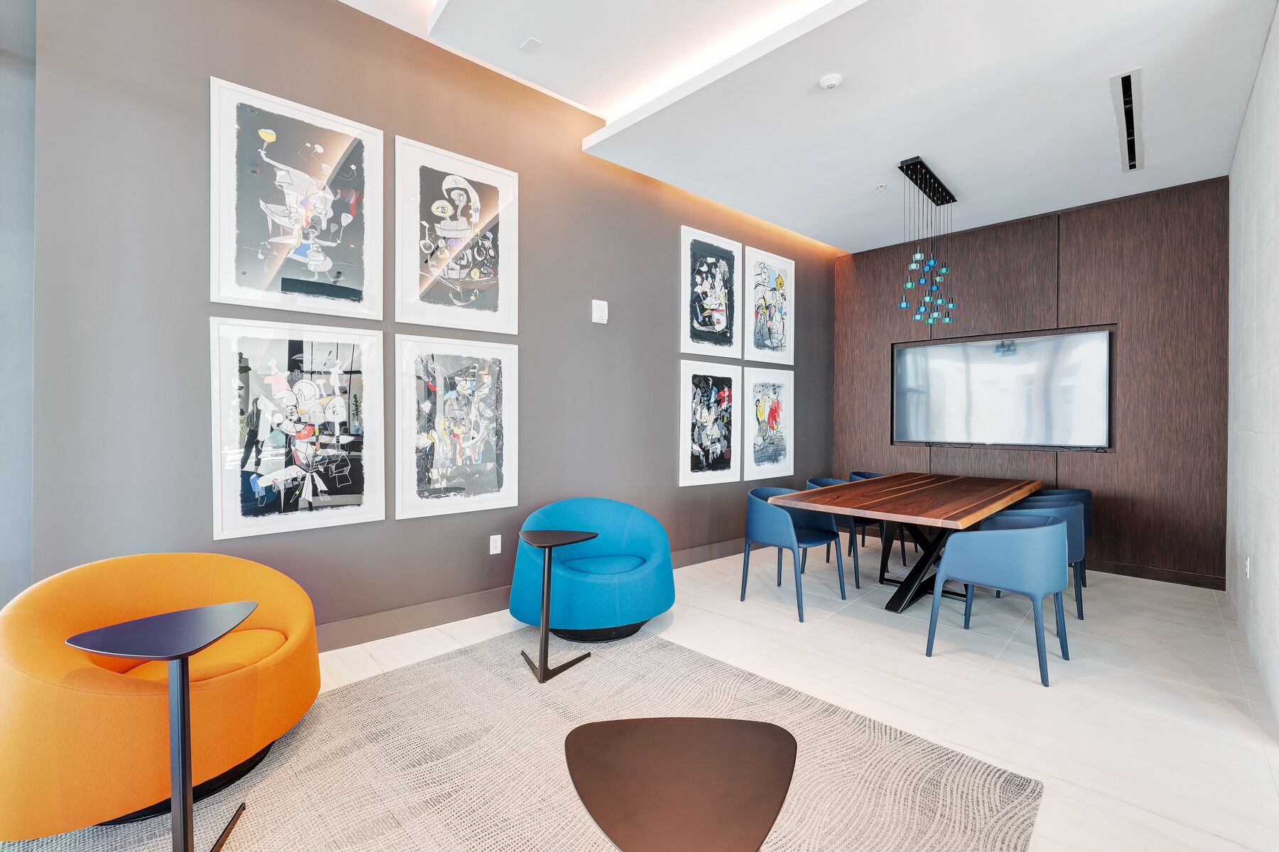 A modern living room with a dining area, featuring a large TV, artwork on the walls, and contemporary furniture.