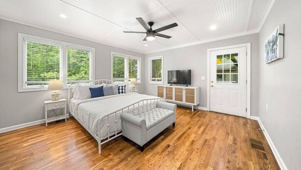 A bedroom with a bed, a nightstand, a TV, and a door. - Serene 3BR home in Historic Downtown Norcross (Norcross)