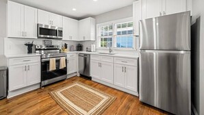 A modern kitchen with white cabinets, stainless steel appliances, and a wooden floor. - Serene 3BR home in Historic Downtown Norcross (Norcross)