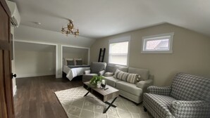 Amplio dormitorio tipo loft con una cama grande, zona de estar con sofá y sillón, y una mesa de comedor.