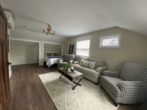 Relax in a spacious living area with a high ceiling, comfortable sofa, and a patterned armchair.