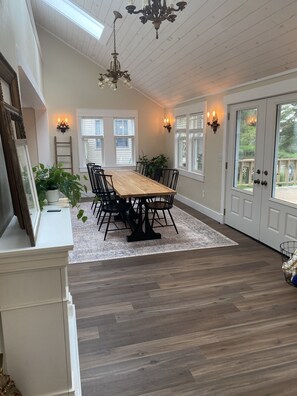 Enjoy meals in this elegant dining area with a long table, high ceiling, and comfortable seating.