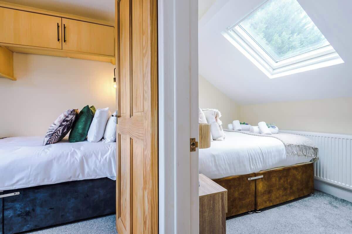 Une chambre avec un puits de lumière, un lit avec une literie blanche et une armoire en bois.
