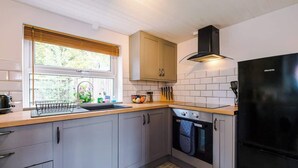 Une cuisine moderne avec des meubles gris, une cuisinière noire et un réfrigérateur noir.