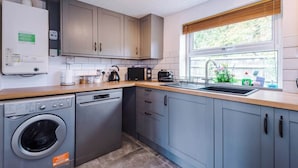 Une cuisine compacte avec des meubles gris, un lave-linge, un lave-vaisselle, un four à micro-ondes et un grille-pain.