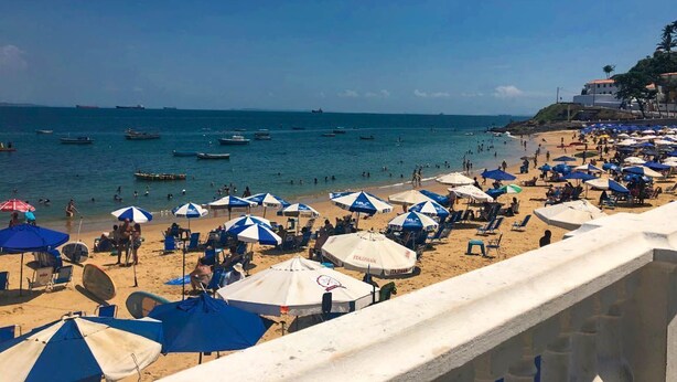 A beach with umbrellas and people.