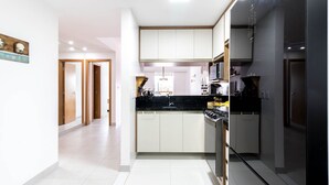 A modern kitchen with white cabinets, a black countertop, and stainless steel appliances. - GB37 Excellent Apt 2 Suites in Guarajuba (Camaçari)