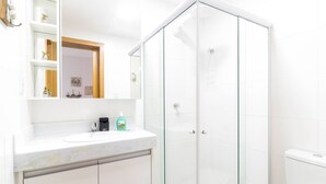 A modern bathroom with a glass-enclosed shower, a white sink, and a mirror above the vanity. - GB37 Excellent Apt 2 Suites in Guarajuba (Camaçari)